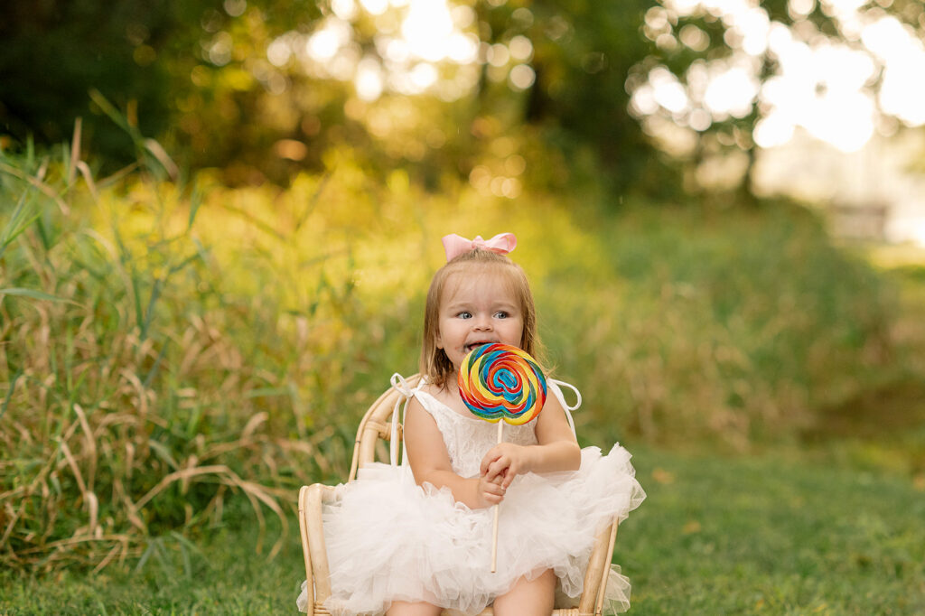 Toddler girl holding colorful lollipop during golden hour session at Mill Creek Preserve in York PA