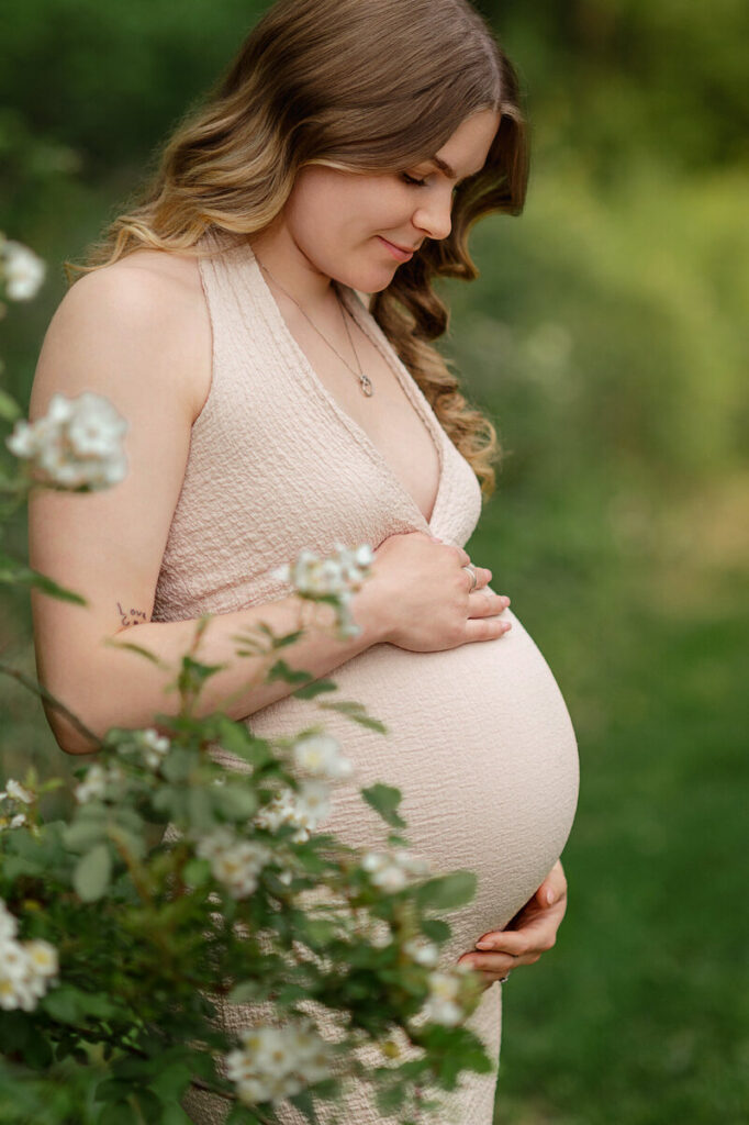 Pregnant mother holding her belly surrounded by greenery during maternity session in York PA