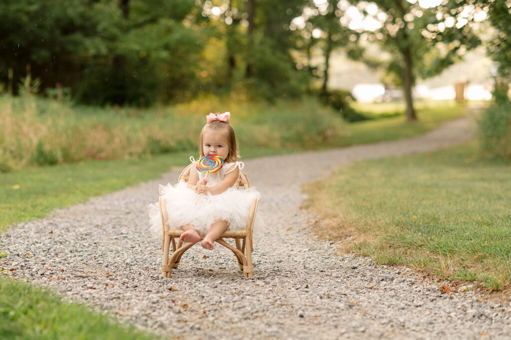 Toddler sitting in chair holding lollipop during milestone session at Mill Creek Preserve in York PA