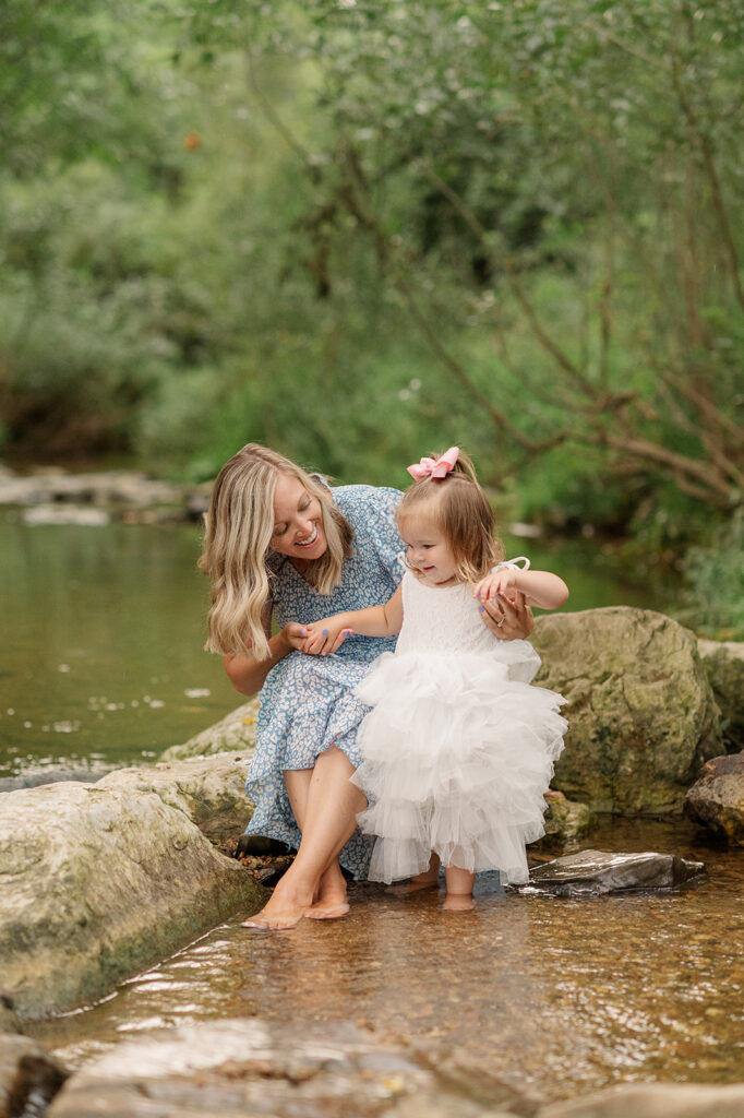Mom and daughter sitting on rocks in creek during photo session at Mill Creek Preserve in York PA
