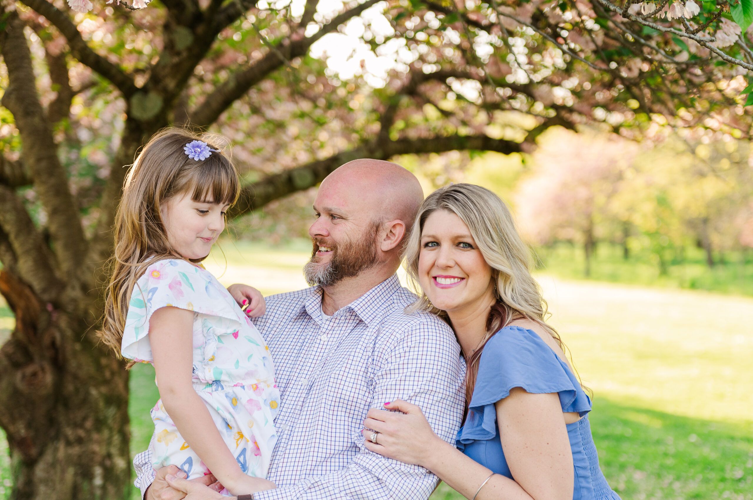 Mother father and daughter posing with cherry blossoms at Lancaster County Central Park by photographer Lancaster, PA