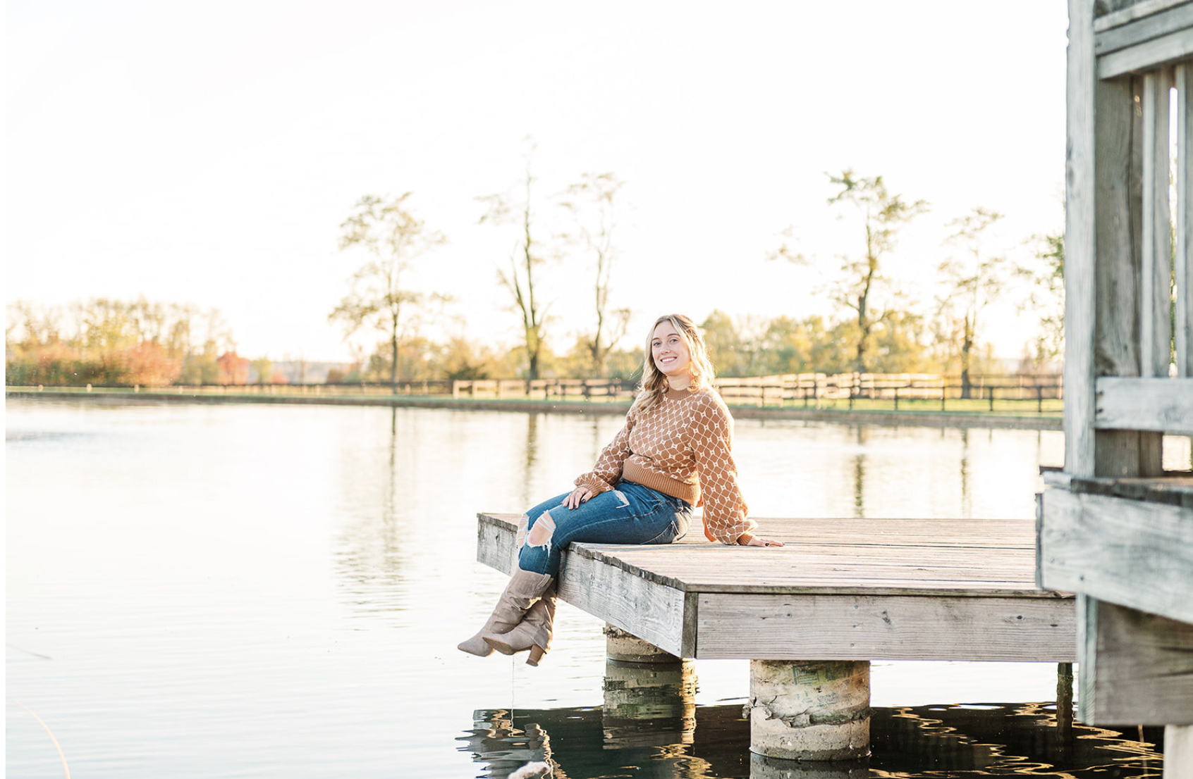 Senior sitting on the dock by the tranquil pond during her senior session at Lakeview Farms