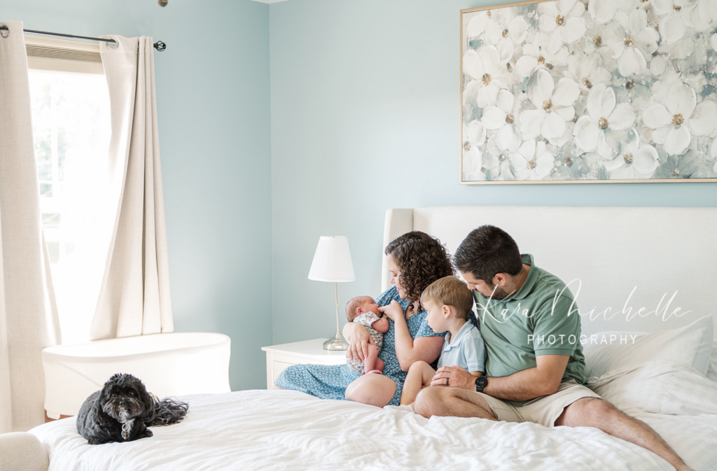 family sitting on their bed together with their dog by newborn photographer york pa