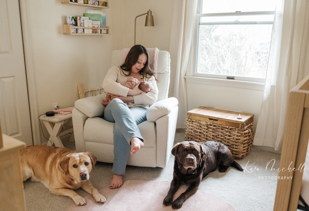 Mother holding newborn with pets in the nursery by photographer york pa