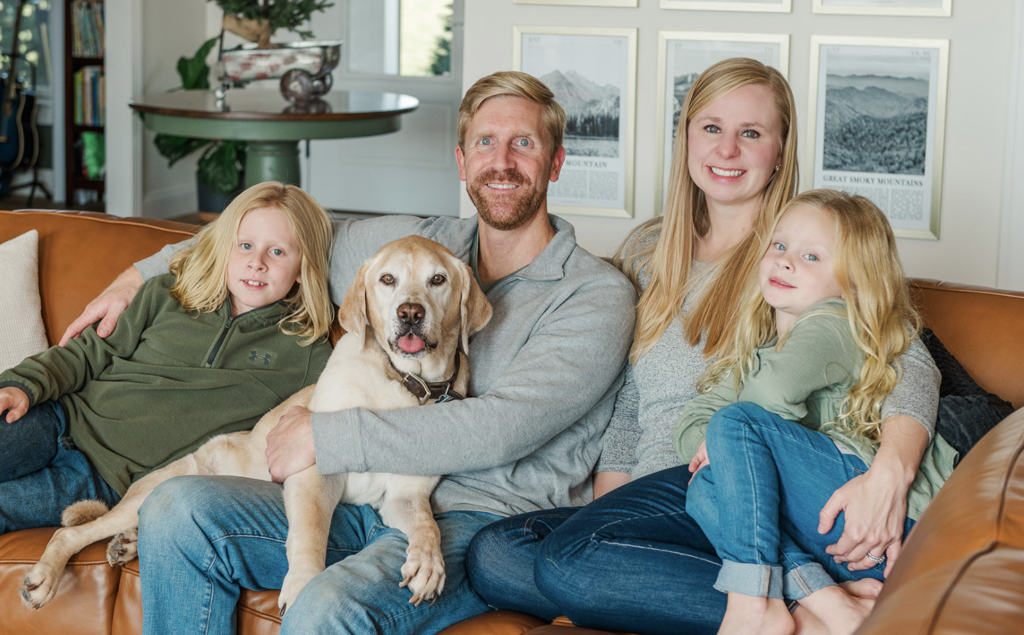 Family posing on couch during in home lifestyle session with their pet by photographer lancaster pa