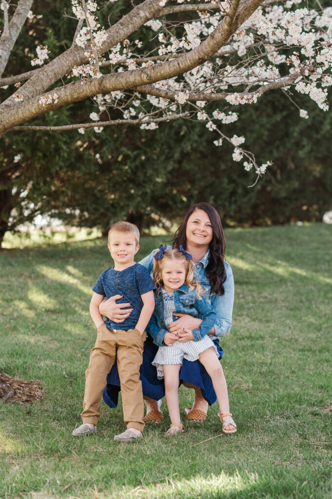 Mother sitting with two children under blooming tree during a spring family session in York PA