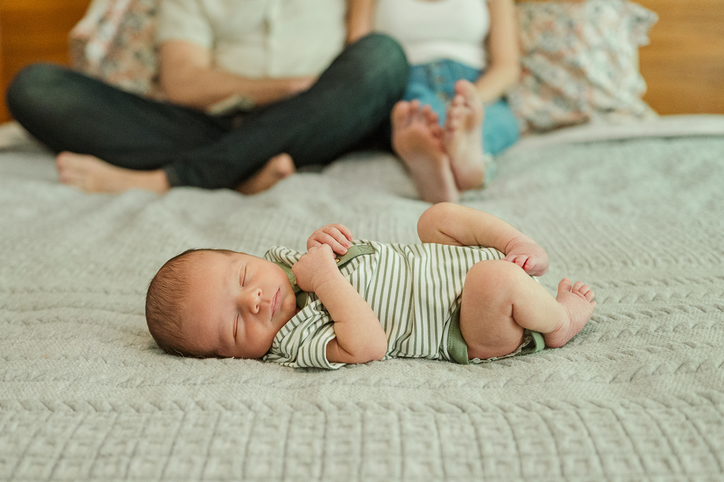 Newborn baby sleeping at the foot of the bed with parents by york and lancaster photographer