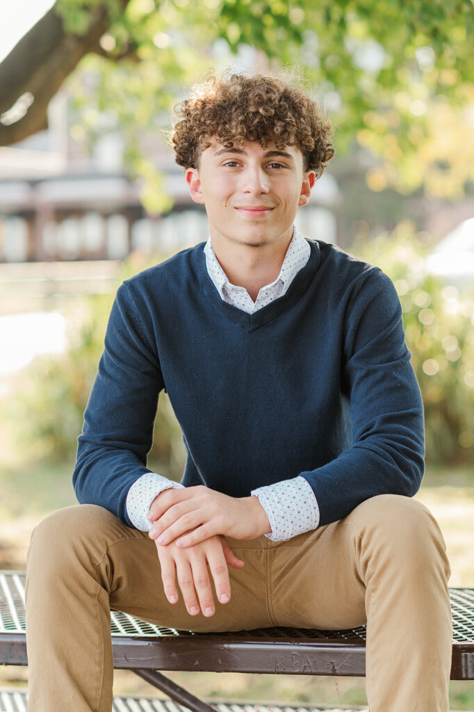 high school senior boy sitting on bench at John Wright Restaurant in Wrightsville PA during senior photo session