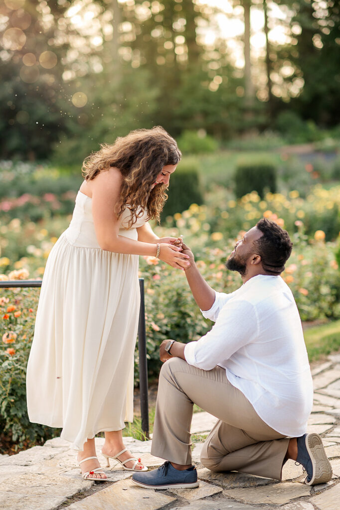 man proposing on one knee at Hershey Gardens with woman smiling during surprise proposal