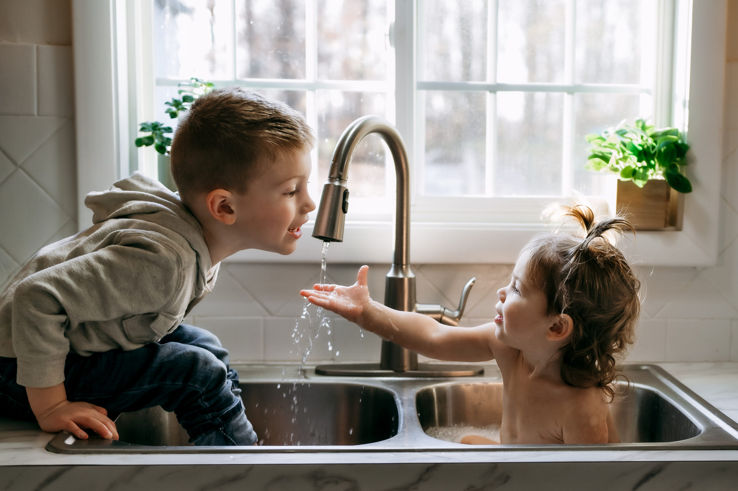 Big brother helping his toddler sister play in the kitchen sink during their Story of Home session in York PA