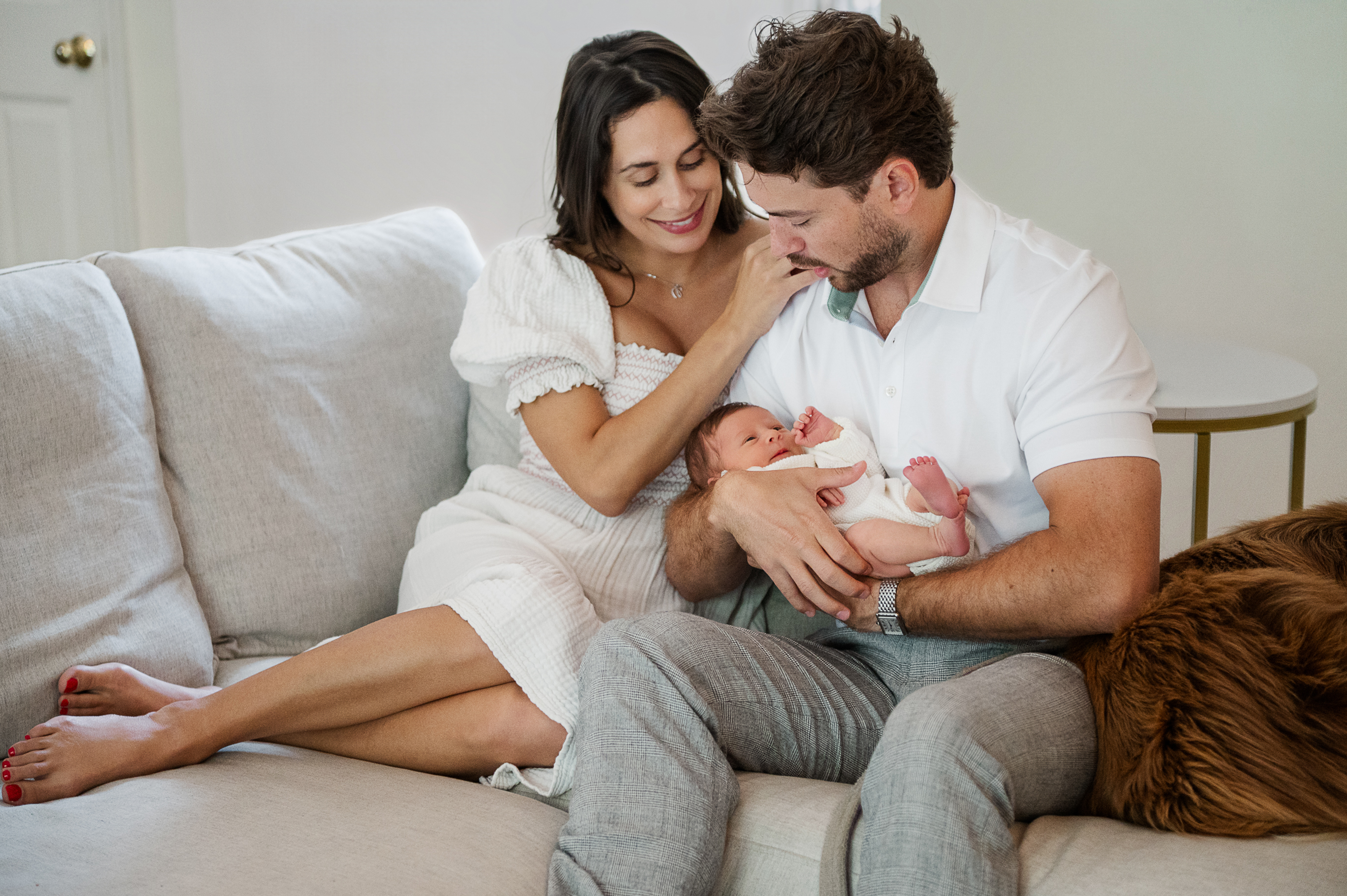 Parents holding their newborn baby on the couch during an in-home newborn session in York, PA.