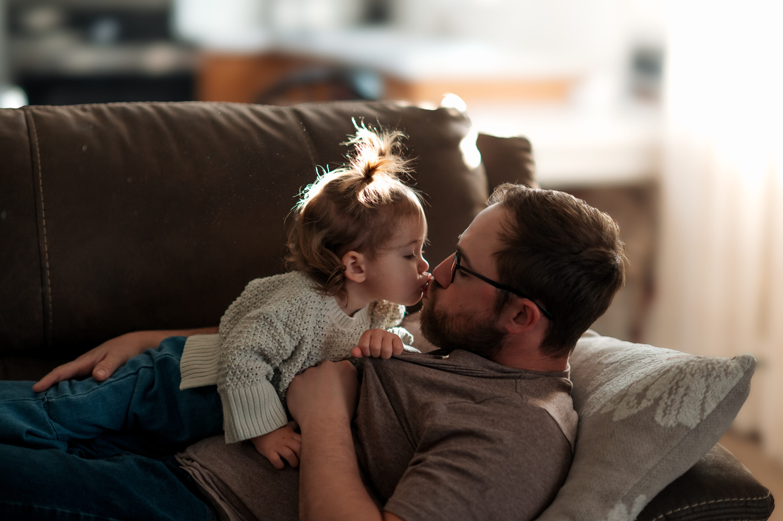 Dad cuddling his toddler on the couch during an in-home family photography session in York PA