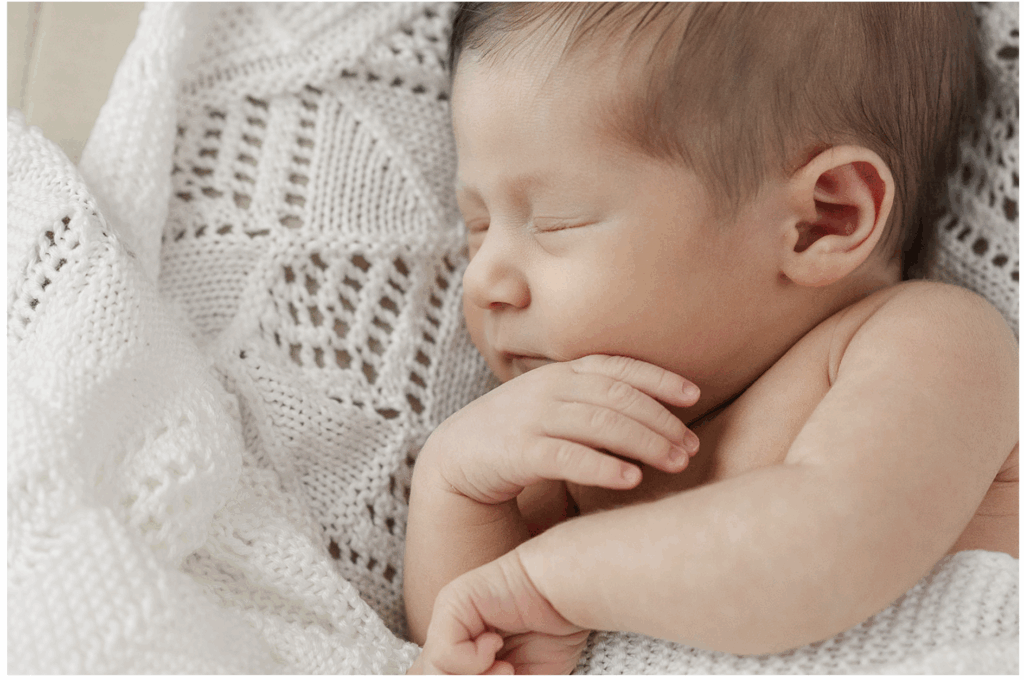 Newborn baby sleeping wrapped in blanket representing what to pack for baby in a hospital bag
