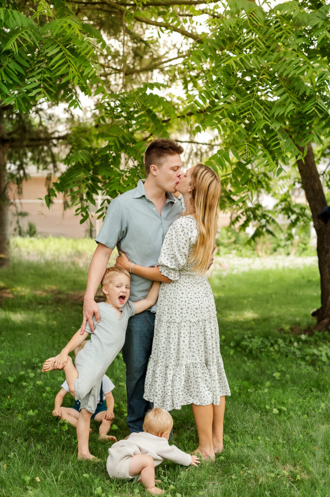 Parents standing together with their young children outdoors during a Story of Home family photography session by Kara Michelle Photography
