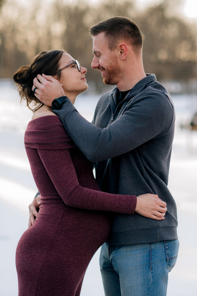 Expecting couple smiling at each other during golden hour maternity session at John Rudy Park in York, PA.