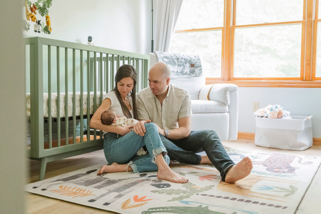 family sitting on nursery floor holding newborn baby during lifestyle session in Lancaster PA