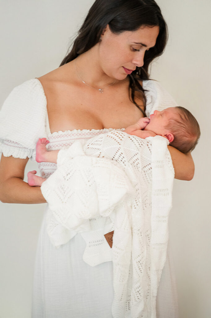 mom standing holding newborn baby during in home session