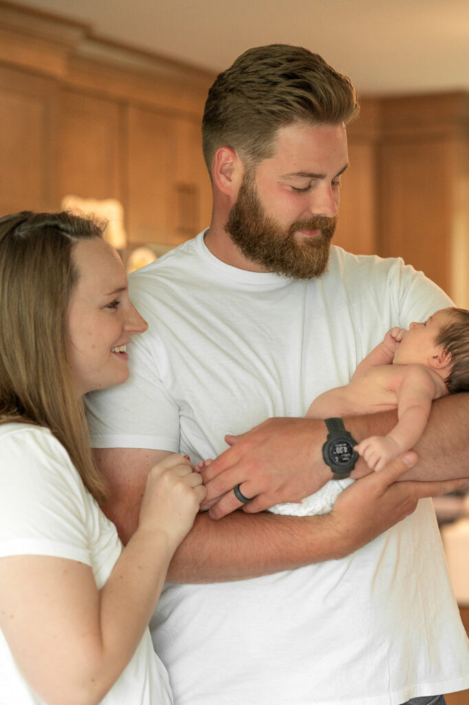 parents holding newborn baby together during in home session
