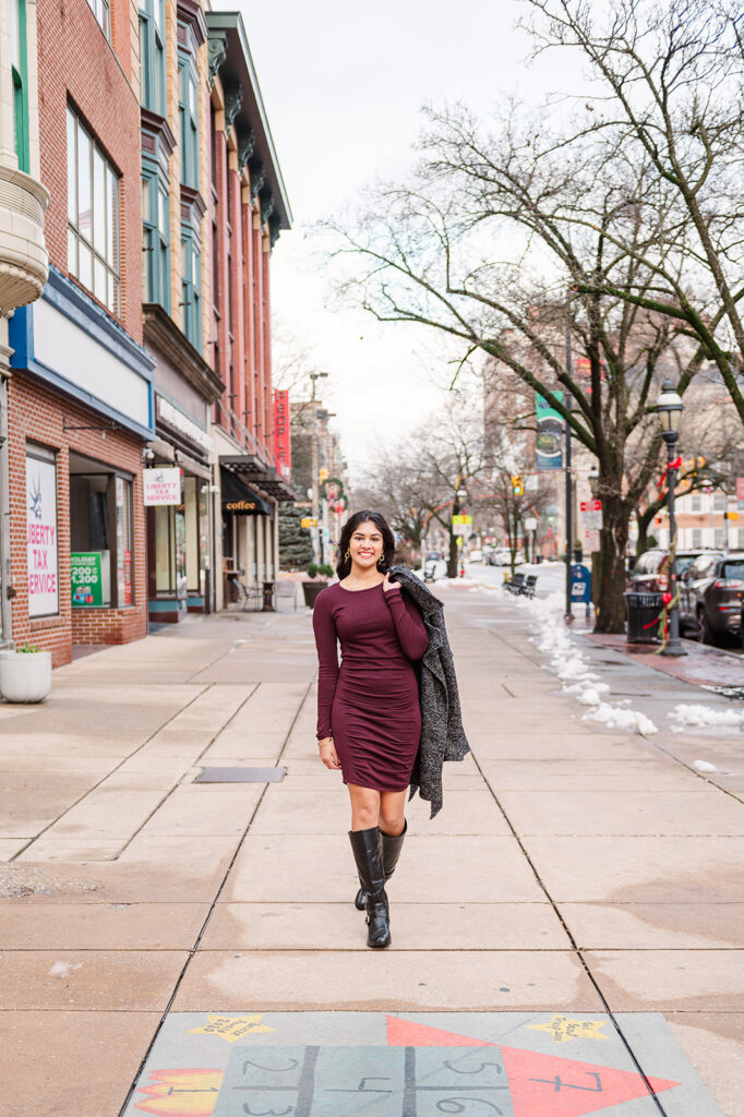 high school senior wearing long sleeve dress and boots during fall downtown senior photo session in York PA
