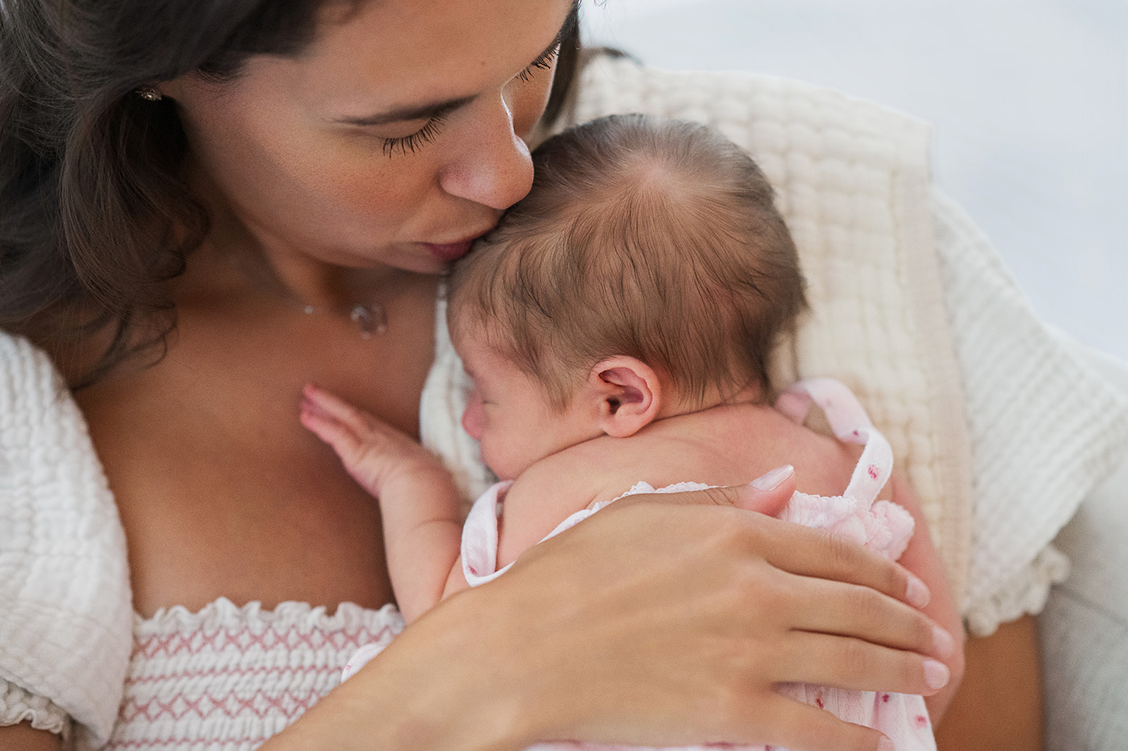 mother kissing newborn baby during first week at home