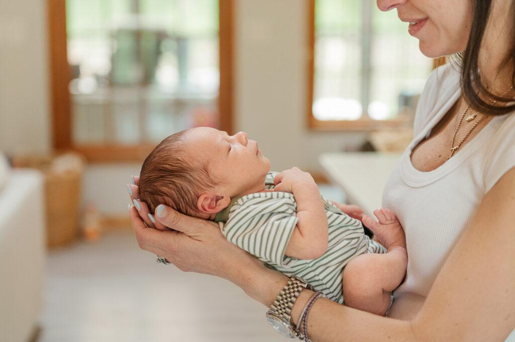 Mother holding newborn by a window with natural light during a home session lancaster pa photographer