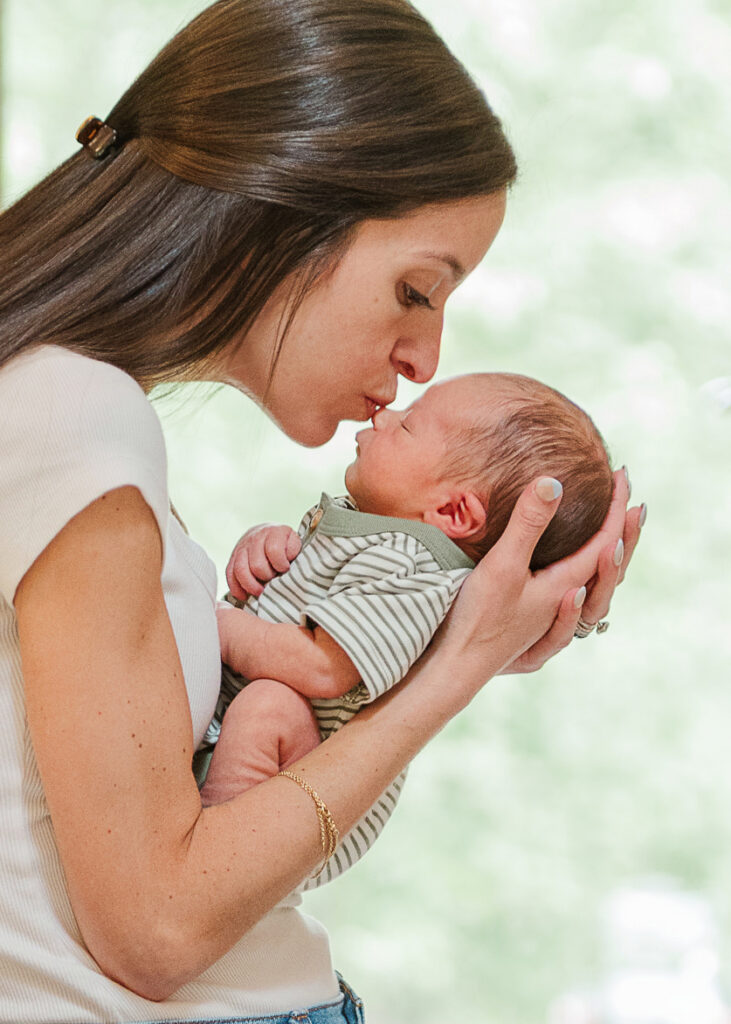 Newborn photos in York PA of mom holding and kissing her baby during an in-home lifestyle session
