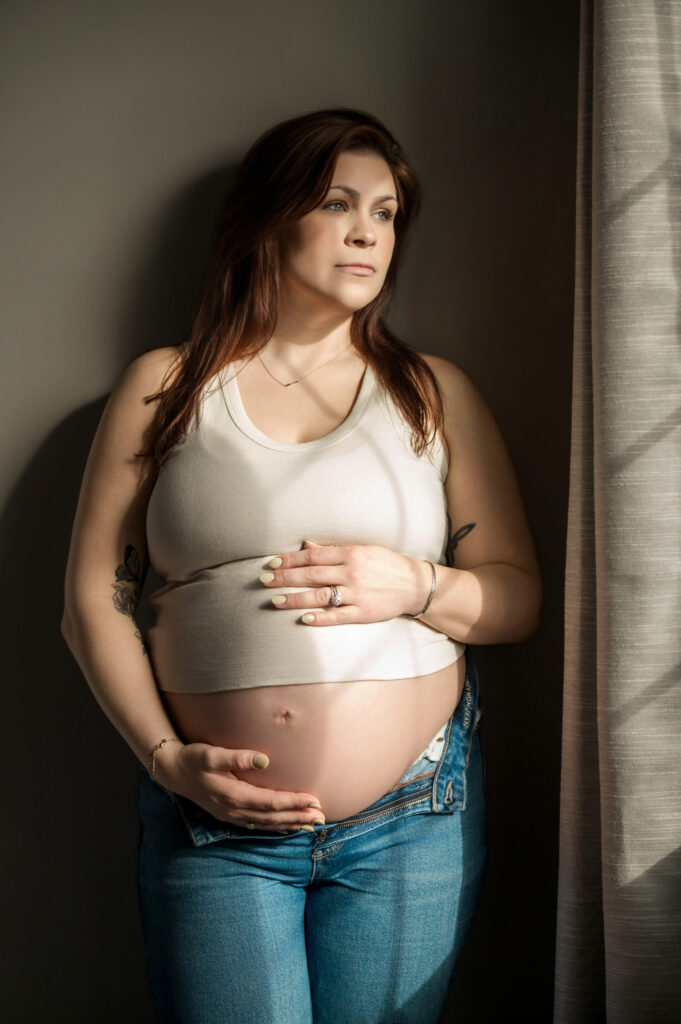 Pregnant mom standing by window during pregnancy in York Pennsylvania