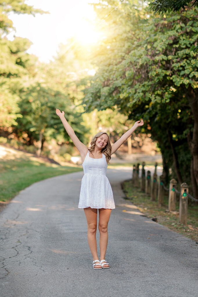 high school senior girl with arms raised smiling during fun outdoor photo session in York PA
