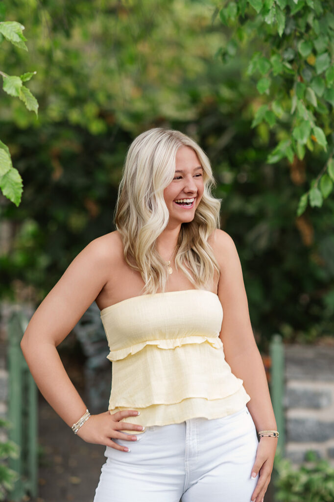 high school senior wearing yellow top and white pants during senior photo session at Hershey Gardens PA