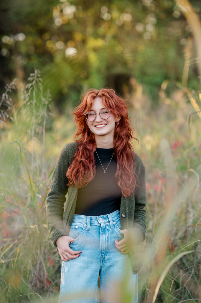 high school senior smiling in a field during natural light senior photo session in Central PA