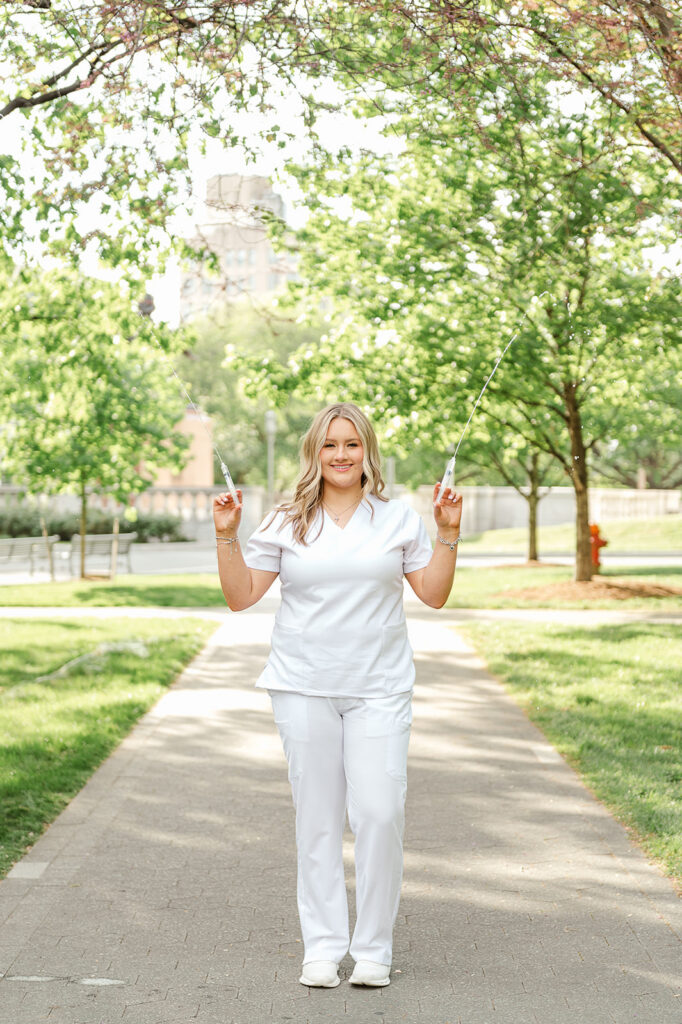 high school senior in nursing scrubs holding syringes during senior photo session at Pennsylvania State Capitol