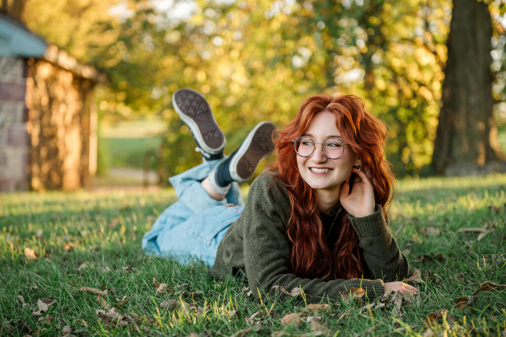 high school senior laying in grass smiling during relaxed senior photo session in York PA