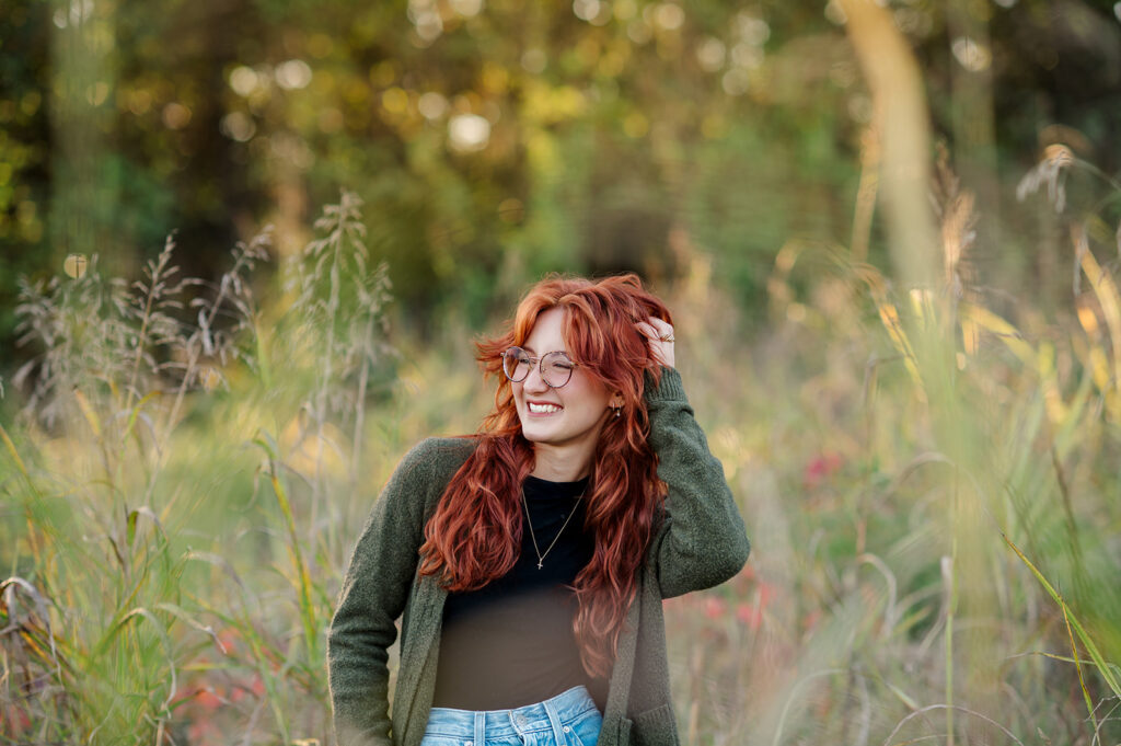 high school senior smiling in green cardigan during outfit change portion of senior photo session in Lancaster PA