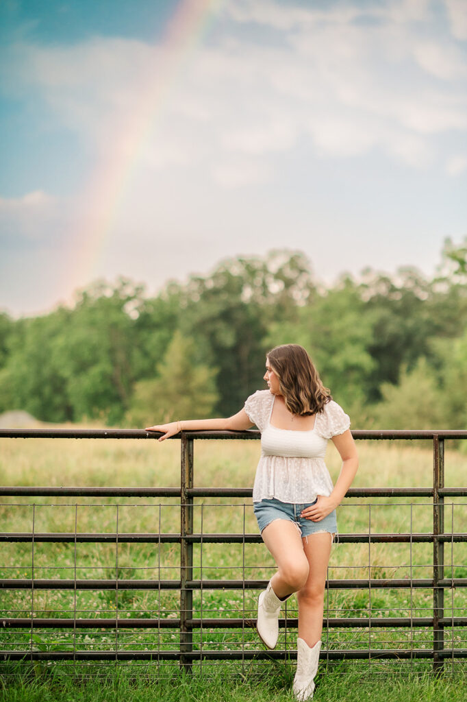high school senior leaning on fence with rainbow during outdoor senior session in York PA