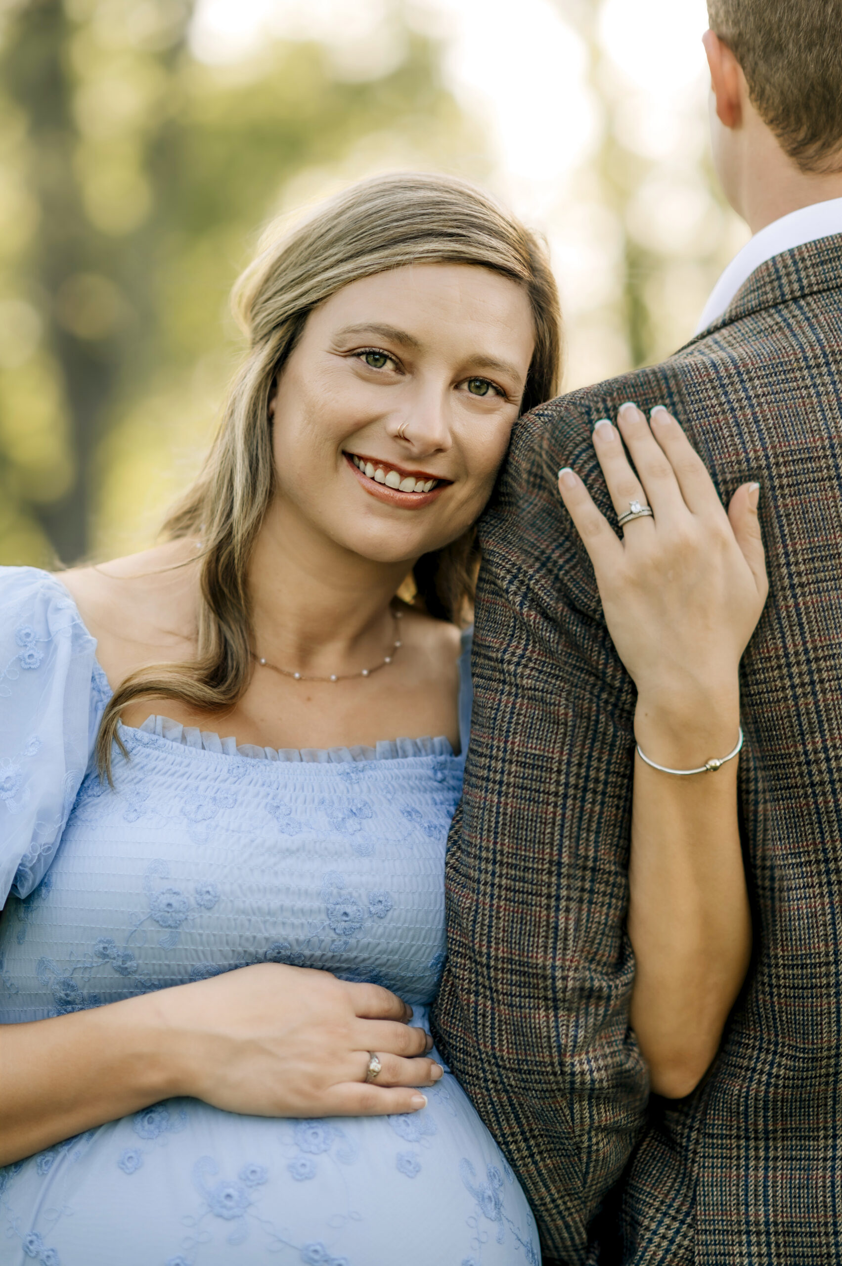 Maternity photos in York PA of a pregnant mom in a blue dress leaning on her partner during an outdoor session