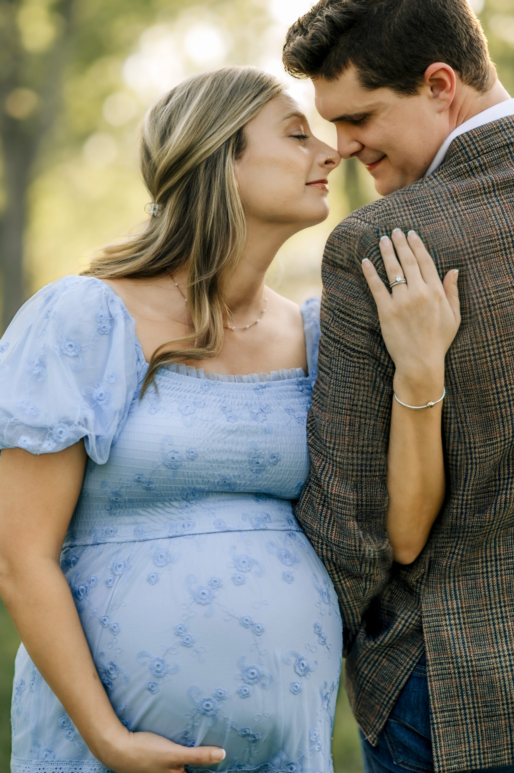 Pregnant couple during maternity session in York PA sharing a close moment with hands on baby bump at sunset