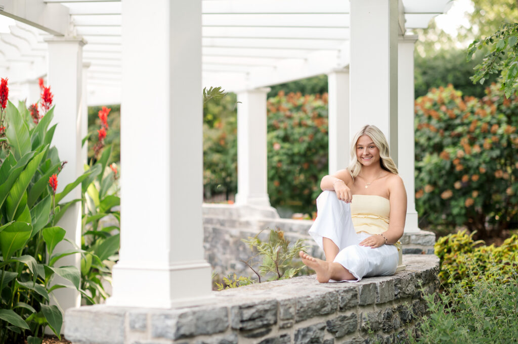 senior sitting near white columns at hershey gardens