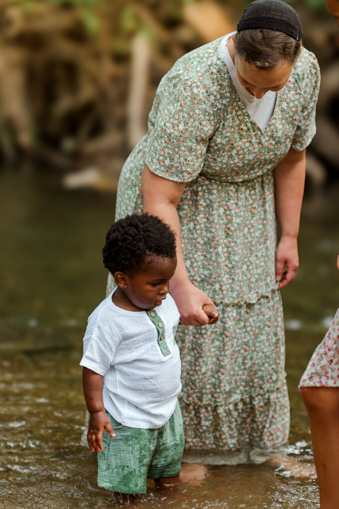 Young child walking through shallow water during a playful outdoor family photo session in York, PA