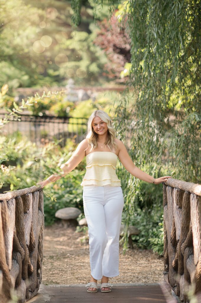 high school senior walking across a wooden bridge at hershey gardens