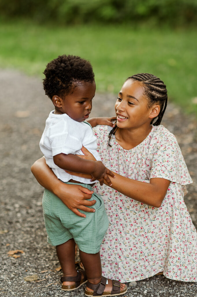 Older sibling holding a younger child during a natural outdoor family photo session in York, PA