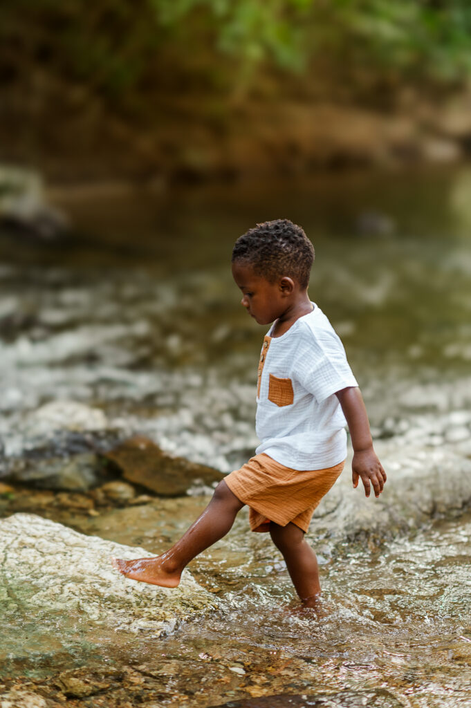 Young child walking through shallow water during a playful outdoor family photo session in York, PA