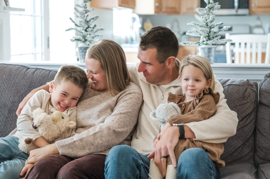 Family sitting together on a couch with two young children during a relaxed in-home family photo session in York, PA