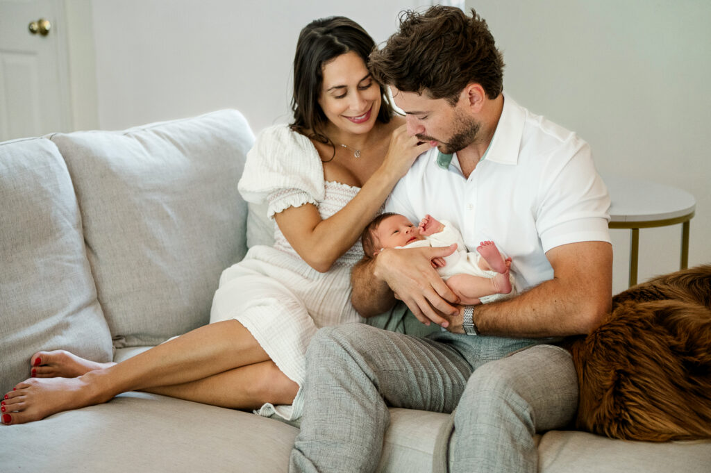 Parents sitting on a couch holding their newborn baby during an in-home newborn session in York, PA