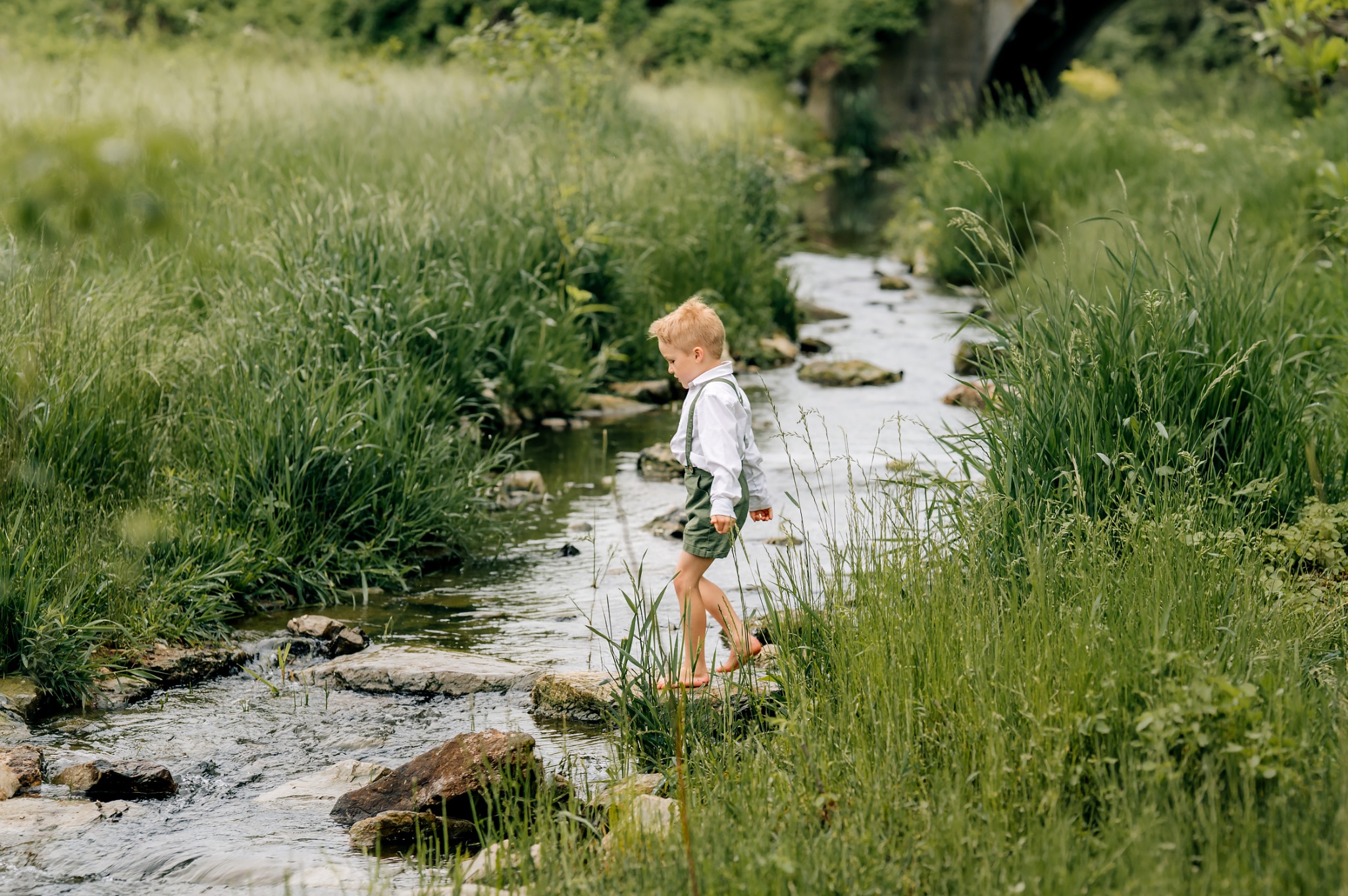 Young boy crossing a creek during an outdoor family photography session
