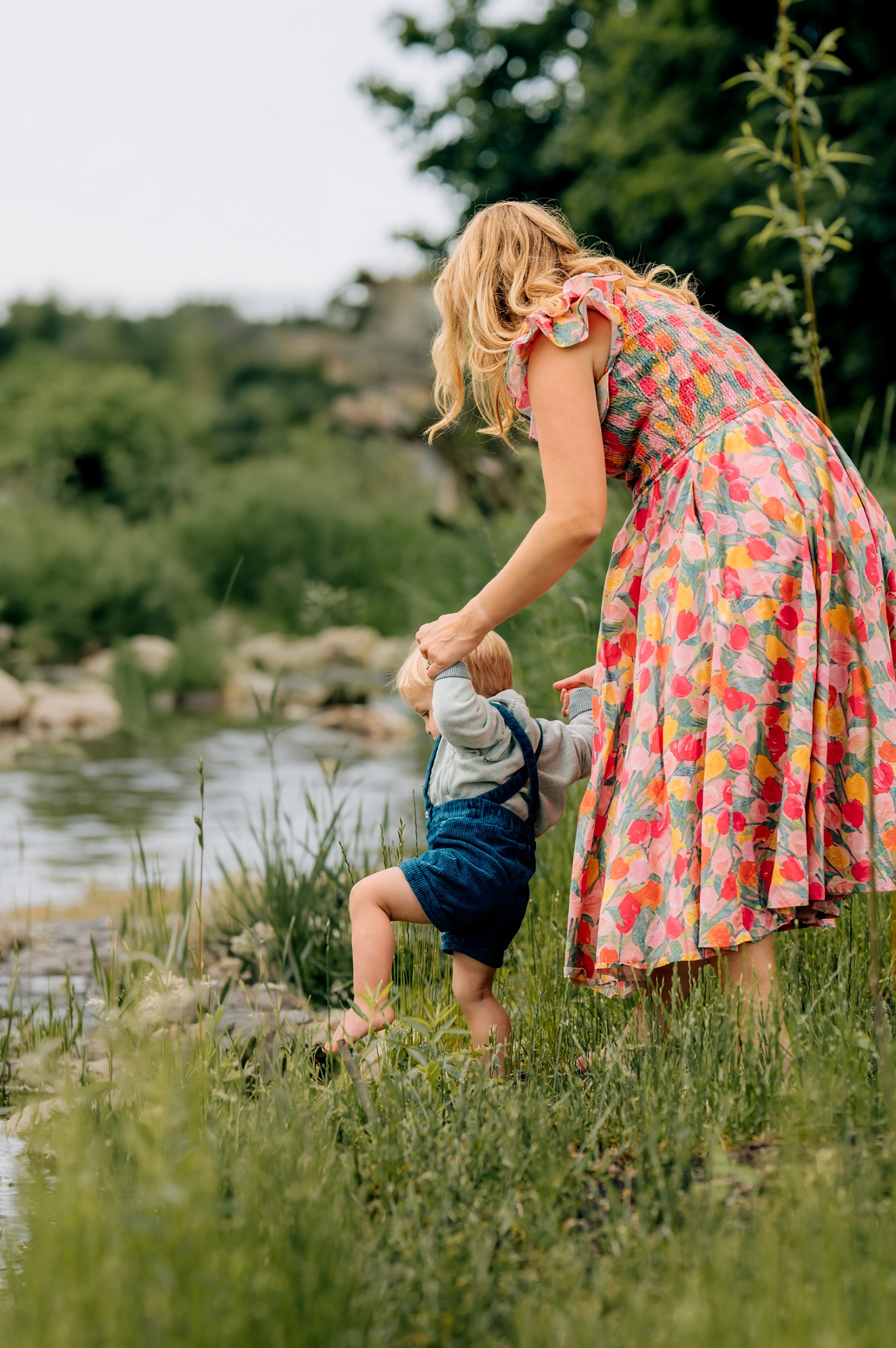 Mother helping her young son explore a creek during a photography session