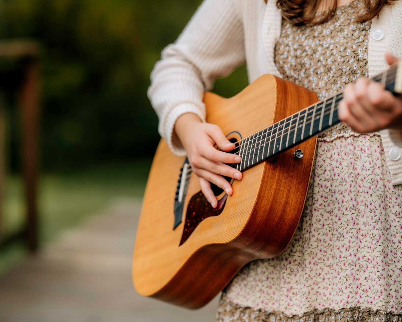 Senior playing guitar behind colorful flowers during a creative senior photography session in Lancaster PA