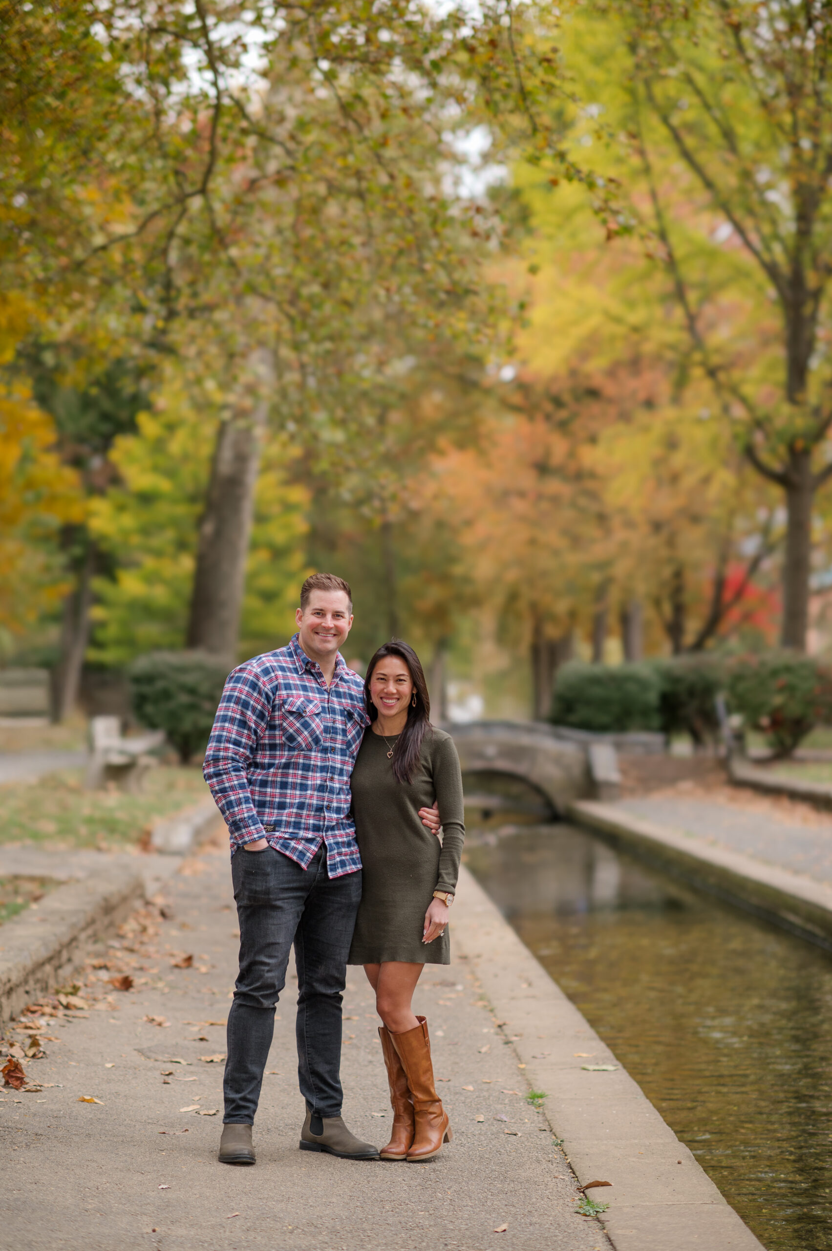 Couple standing together beside the stream and stone bridge during a fall session at Lititz Springs Park in Lititz, PA.