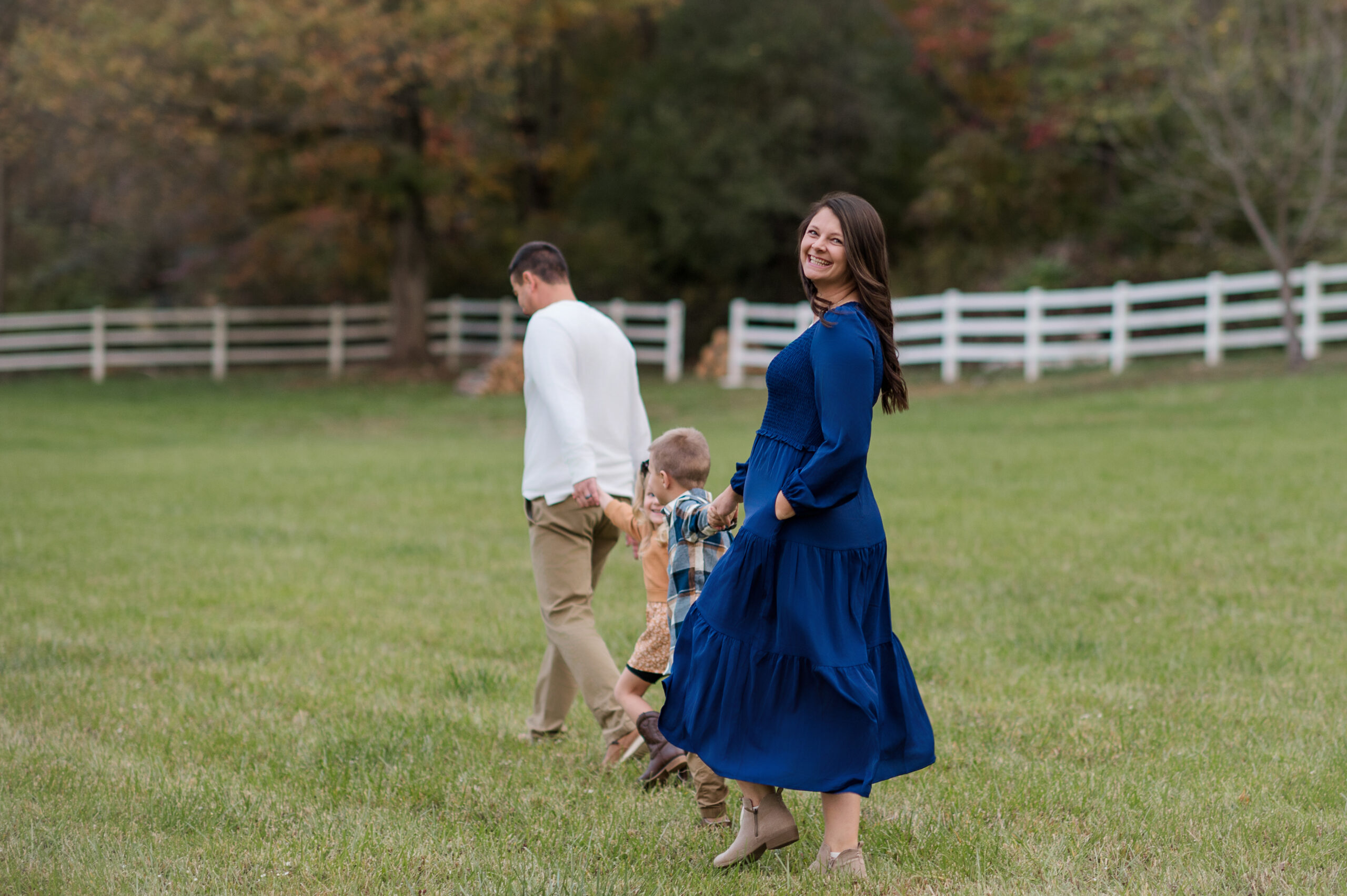Mom smiling while walking with her family through a field during a candid fall family photography session in York, PA.