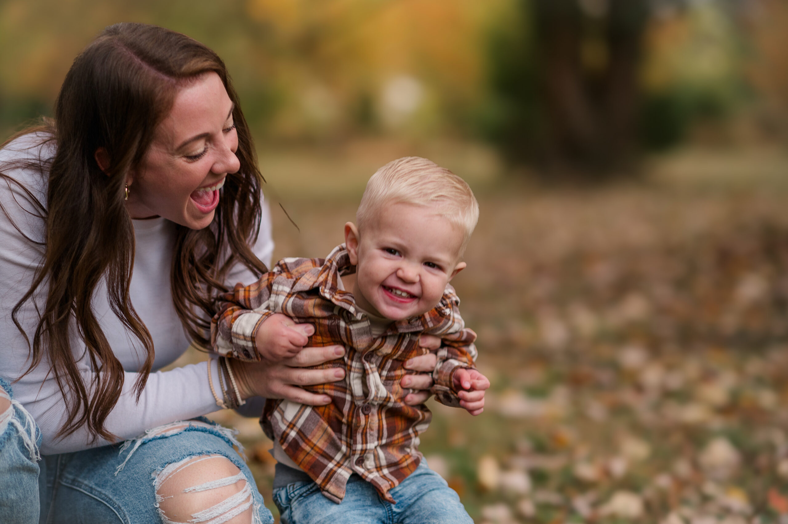 Mom laughing with her smiling young son during a candid fall family photography session in York, PA.