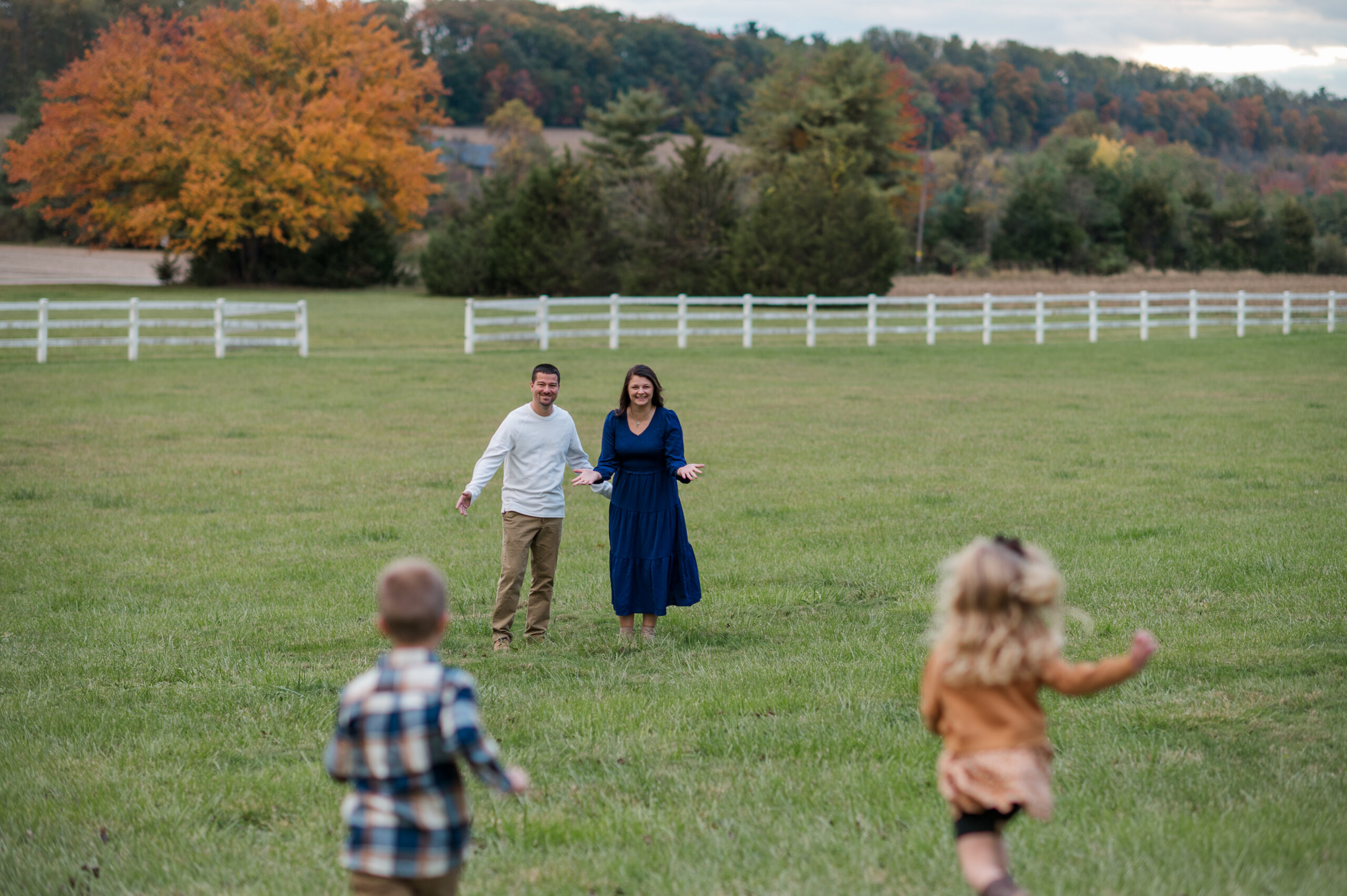Two children running toward their parents through a grassy field during a fall family photo session in York, PA.